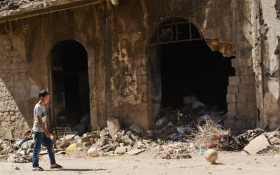 Barn gengur fyrir framan rústir í Sýrlandi